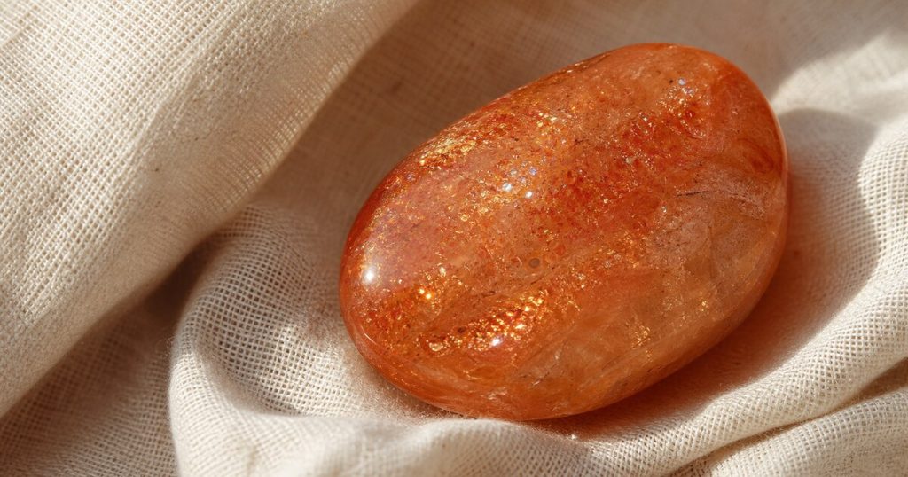ซันสโตนสีส้มทองมีประกายระยิบบนผ้าลินิน
